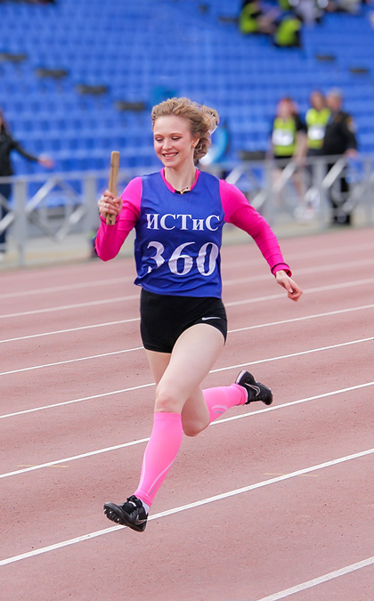 Студентка, бегущая по дорожке стадиона
